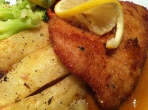 Fried pork-chop garnished with a lemon twist for dinner. 