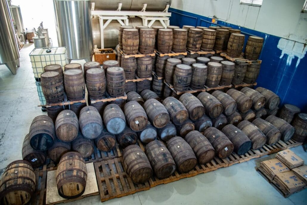 A warehouse with stacks of wooden barrels organized on pallets, reminiscent of a stop on the Nassau Rum and Food Tour.