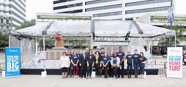 Volunteers from the New Orleans Chapter of Second Harvest Food Bank all pose by the world's largest Carnival cruise ship made out of cans, sponsored by Carnival Cruise Line near Poydras Street side of the Mercedes-Benz Superdome in New Orleans on Monday, December 21, 2015. (Photo by Peter G. Forest)