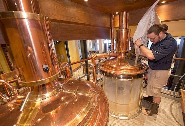 Carnival Vista Brewmaster Colin Presby pours malt into a mash tun located in the RedFrog Pub's brewery house