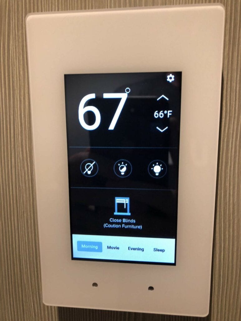 A touchscreen thermostat panel aboard the Celebrity Edge displays a cozy 67°F. It offers controls for fan, lighting, and blinds, perfect for setting the cabin's ambiance. Conveniently labeled buttons like "Morning," "Movie," "Evening," and "Sleep" make it effortless to tailor your cruise ship experience.