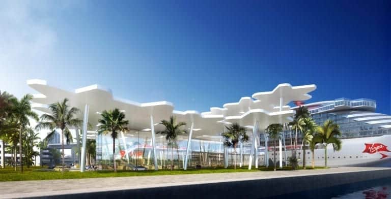 A modern waterfront building with a unique white, cloud-shaped roof structure surrounded by palm trees stands as an architectural gem in Miami. Nearby, a large cruise ship is docked under a clear blue sky, all lit beautifully by the sunlight. This could be the perfect new home for maritime enthusiasts.