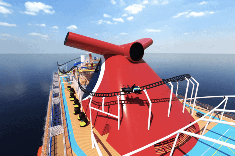 A new Carnival cruise ship deck features a large red funnel with a roller coaster track wrapping around it. The vessel is surrounded by calm, open water under a clear sky with scattered clouds. Various seating and deck structures are visible, enhancing the experience.