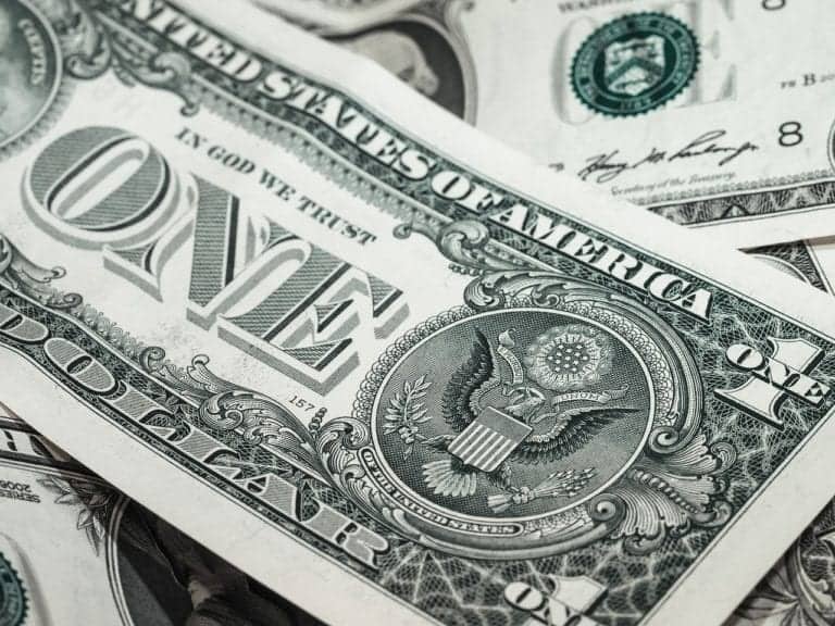 Close-up of overlapping one-dollar bills showing the front side with "United States of America" and "In God We Trust," along with the Great Seal featuring a bald eagle—a sight familiar to cruisers collecting travel advice for their next adventure.