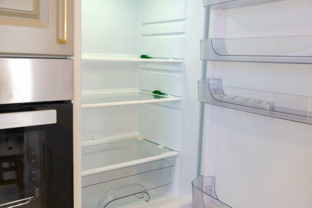 An open, empty refrigerator with three shelves, a clear drawer at the bottom, and door compartments awaits your next steps in meal preparation.