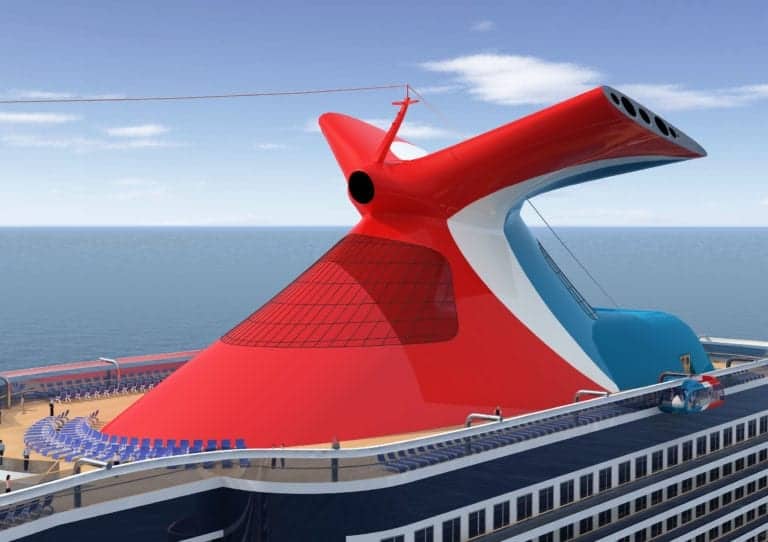 A close-up view of a red and white Holland America cruise ship funnel on the upper deck, featuring a large, winged design. Blue panels and seating areas are visible on the deck below. The ship is surrounded by calm ocean waters under a clear, blue sky.