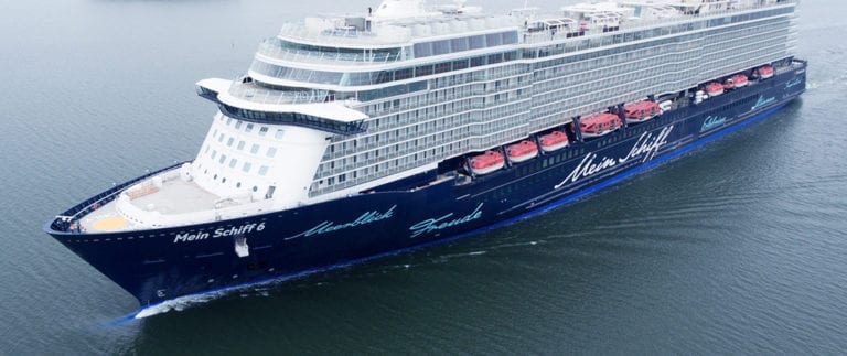 A large cruise ship named "Mein Schiff 6" sails on calm waters. The ship has multiple decks, and lifeboats are visible on the sides. Its name is written prominently on the side in blue and white text, ensuring that passengers know it’s not a false alarm: "No Virus" onboard.