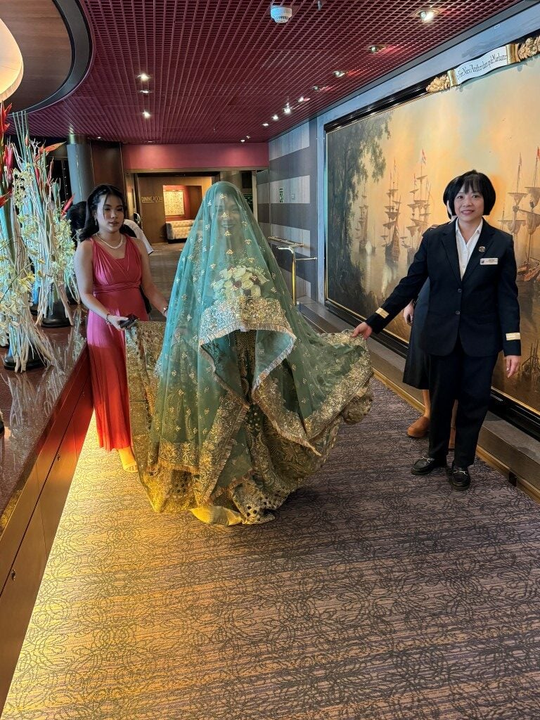 A woman wearing a green sari in the lobby of a cruise ship on a solo cruise.