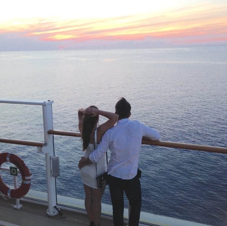 First cruise as a couple standing on the railing of the cruise ship.