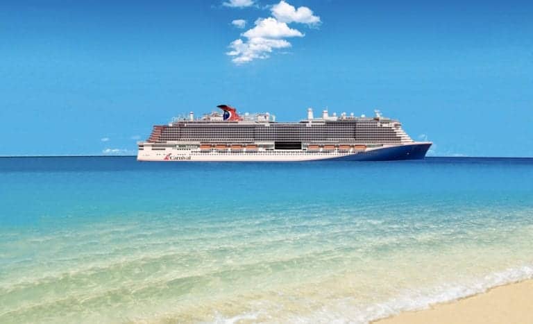A large cruise ship is sailing on clear blue water with a blue sky and a few clouds above. The ship, labeled with the word "Carnival," is part of the renowned Carnival Cruise Line fleet, seen from a distance with a sandy beach in the foreground.