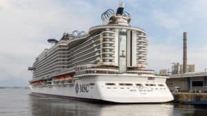 A large white cruise ship, named "MSC Seaview," docked at a Caribbean homeport. The ship, operated by MSC Cruises, has multiple decks with lifeboats on the side. Industrial buildings and a large smokestack are visible in the background under a partly cloudy sky.