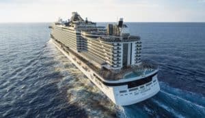 A large MSC cruise ship sails on a vast ocean, leaving a wake behind it. The ship, often seen on routes between Europe and the U.S., boasts multiple decks, outdoor pools, and balconies. The sky is clear, and the sun shines brightly, creating a serene maritime scene.