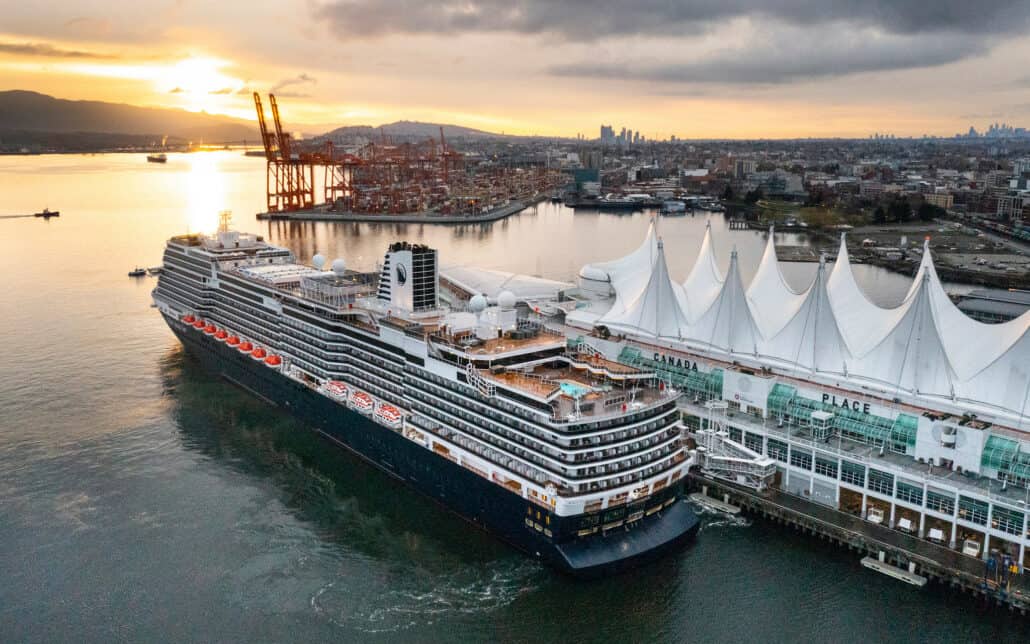 A large cruise ship docked at Canada Place in Vancouver, with cranes and industrial buildings in the background. The sun is setting, casting a warm glow over the harbor and city skyline. A Starlink satellite streaks across the partly cloudy sky, blending technology with the serene evening scene.