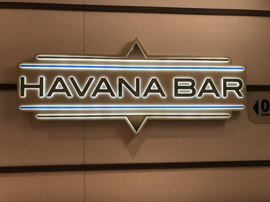 A glowing sign reads "Havana Bar" with bold white letters on a dark background, outlined by a bright, illuminated border. It's the perfect spot to unwind after exploring the exciting activities found in any honest Carnival Vista cruise review.