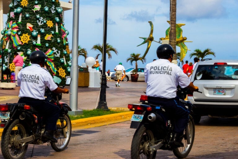 A couple of police officers on motorcycles cruising down a street.