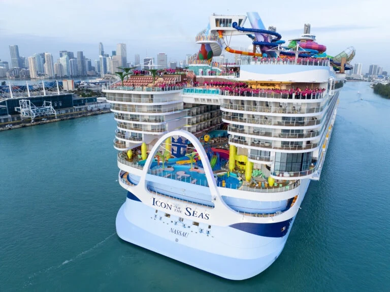 The Icon of the Seas, a large cruise ship, docked in a city.