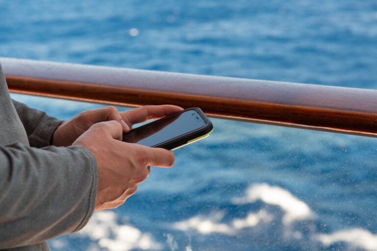 A man holding a cell phone on a Princess cruise ship.