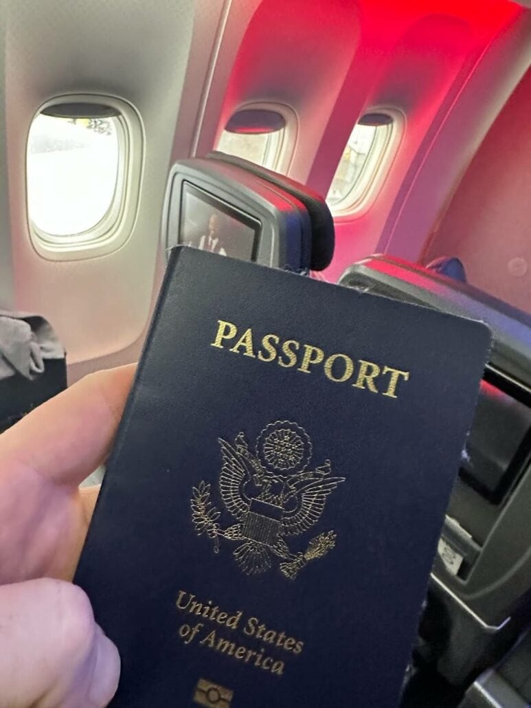 A person holding a passport in front of an airplane, ready to embark on a cruise.