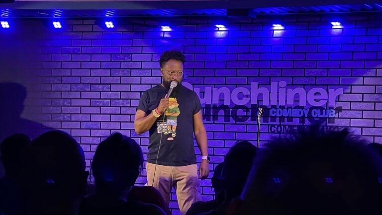 A man is standing in front of a stage with a microphone.