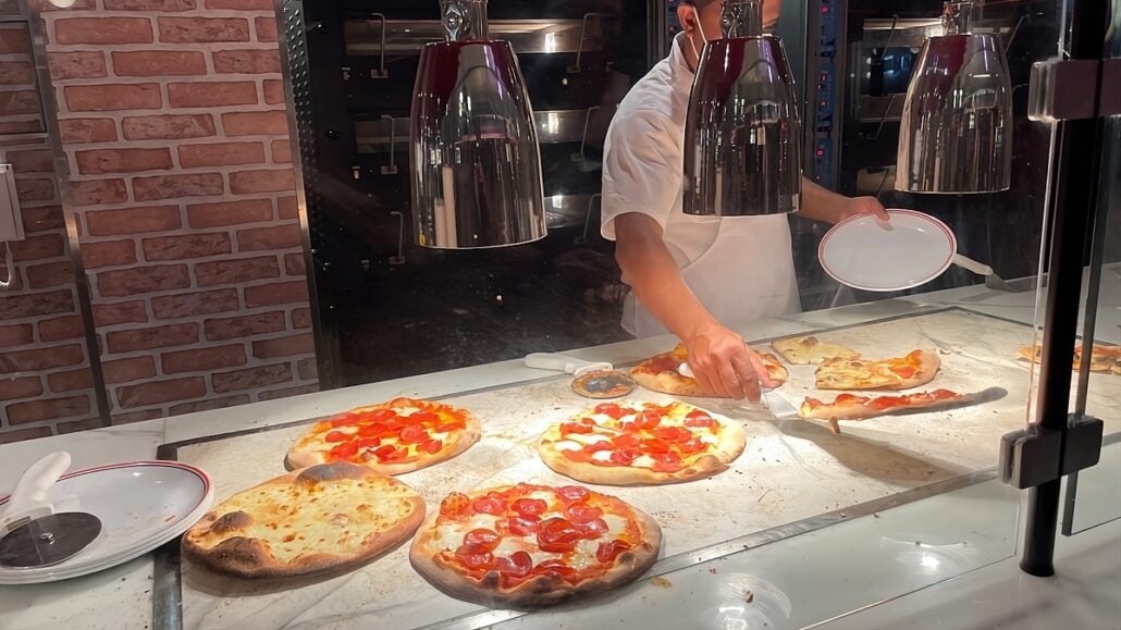 A man is preparing pizzas in a restaurant.
