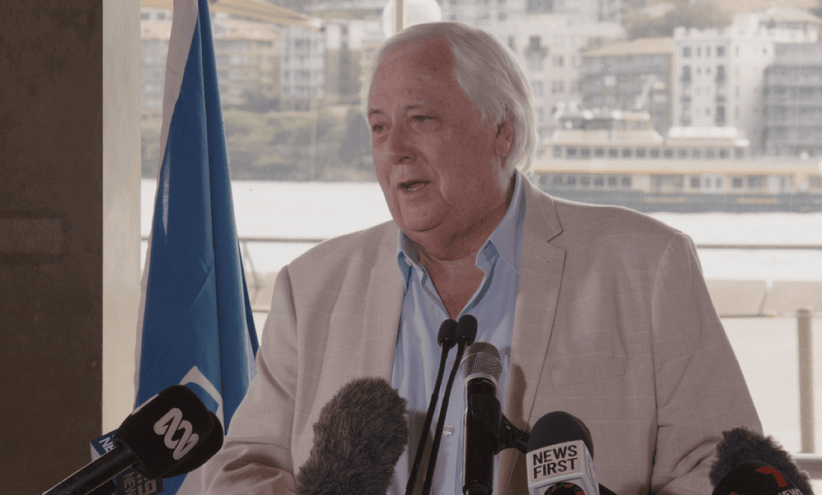 An Australian billionaire in a suit speaking into microphones.