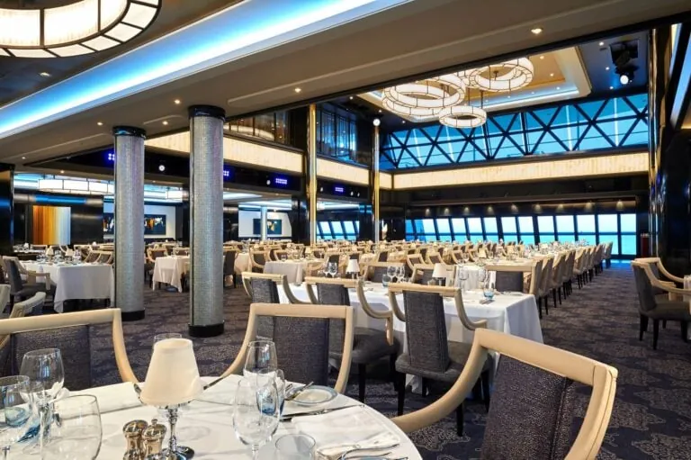 A modern and elegant cruise ship dining room set for a Norwegian Cruise Line menus meal, featuring stylish decor with blue lighting accents.
