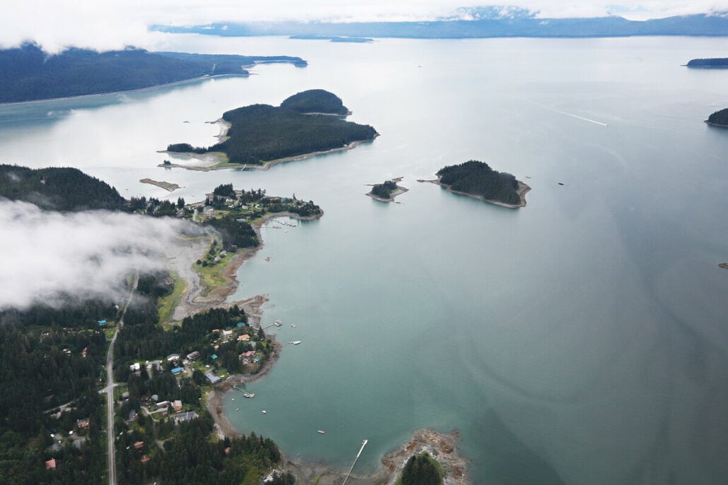 Aerial view of a coastal area with small islands, a residential settlement along the shoreline, and Ship-Free Saturdays impacting the serene waters.