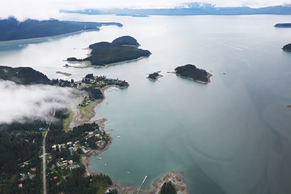 Aerial view of a coastal area with small islands, a residential settlement along the shoreline, and Ship-Free Saturdays impacting the serene waters.