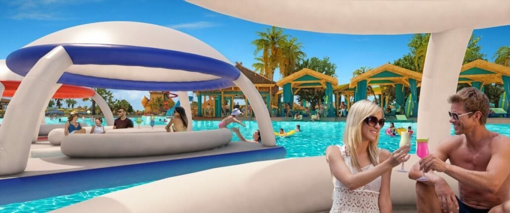 People relax in a pool area with inflatable loungers and drinks. Palm trees and cabanas are in the background, and a few other people are swimming and socializing. Carnival Reveals Starfish Lagoon is the perfect celebration spot at Celebration Key for all ages to enjoy.