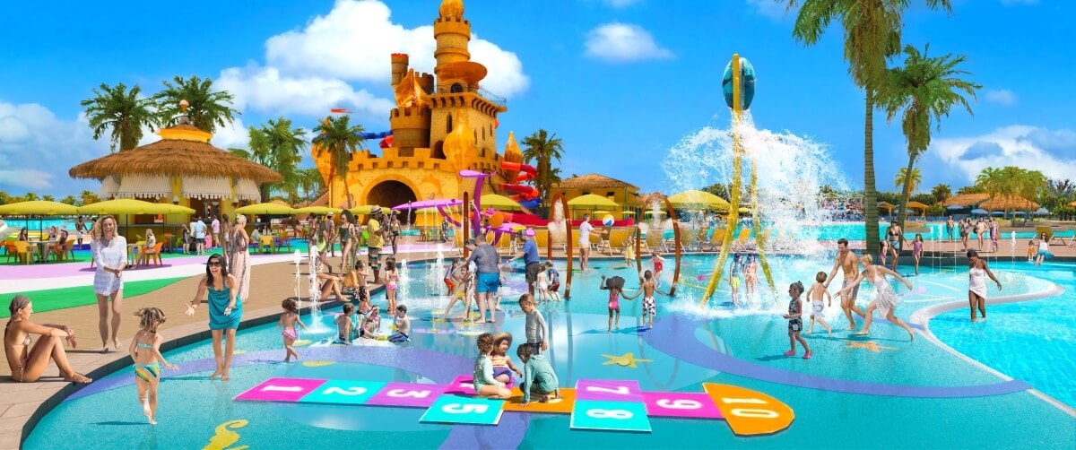 Families and children enjoy various activities in the vibrant Carnival Reveals Starfish Lagoon, featuring a splash pad, hopscotch, a water fountain, and a castle-themed structure. Palm trees and umbrellas add to this family-friendly attraction's appeal.