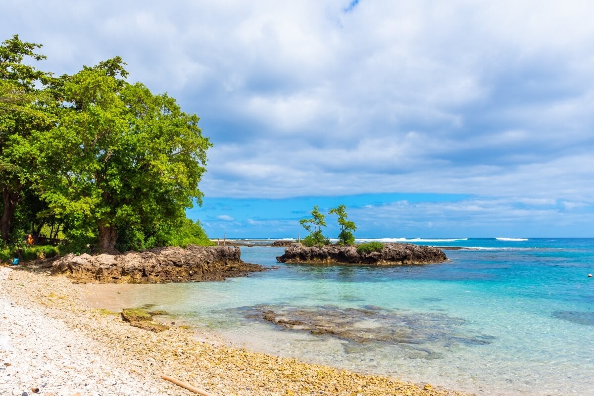 A tropical beach with clear blue waters, small rocky islands, and lush green trees under a partly cloudy sky became the perfect getaway for Aussie youths enjoying their time off from the P&O Cruise Ship.