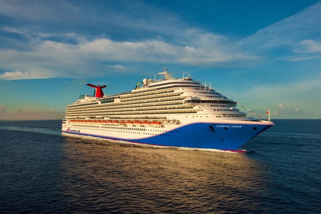 A large cruise ship sails on open water under a clear sky, with the words "Carnival Dream" visible on its side, as the Carnival crew members ensure a smooth and enjoyable journey for all passengers.