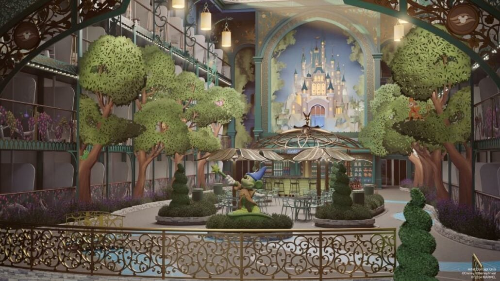 Welcome to the Imagination Garden, an indoor space adorned with decorative wrought iron railings, lush topiary trees, and a cozy seating area with tables and chairs. A painted castle backdrop adds a touch of fantasy, while a central wizard statue completes this enchanting Disney-inspired scene.