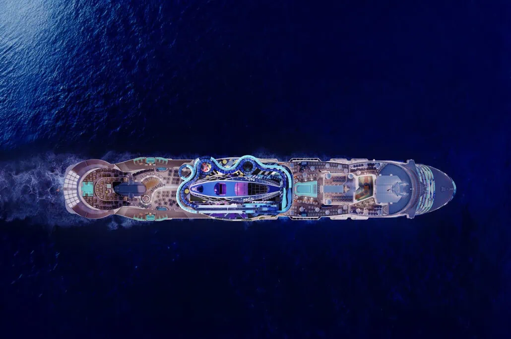 Aerial view of the Norwegian Luna, a large cruise ship with various amenities on deck, sailing through dark blue water.