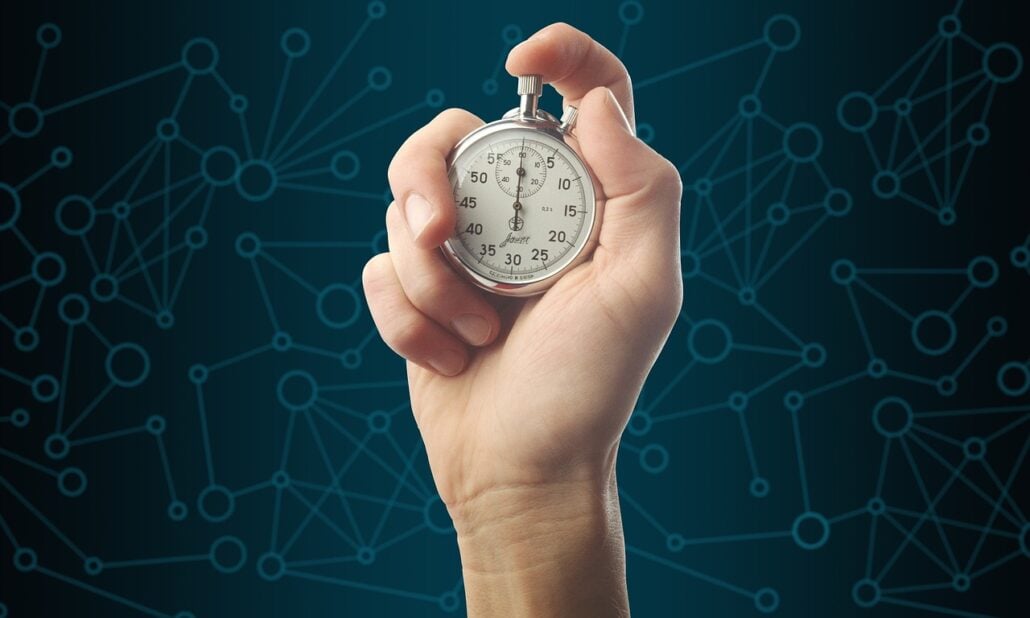 A hand holds a silver stopwatch against a blue background with a network pattern, marking the countdown to an exciting family vacation. The stopwatch displays the time.