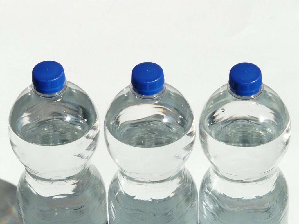 Three clear plastic bottles filled with water, each with a blue cap, are lined up horizontally against a white background. Imagine finding these on Princess Cruises, where the water bottle price might be 200% higher than usual.