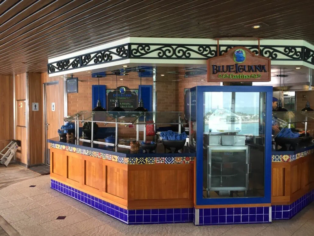 Located on the Carnival Freedom, "Blue Iguana" is a lively place to eat. With its vibrant decor and tiled counter displaying condiments and napkins, it’s the perfect spot for tasty tacos and burritos. The wood-themed interior offers soothing water views through a door in the background.