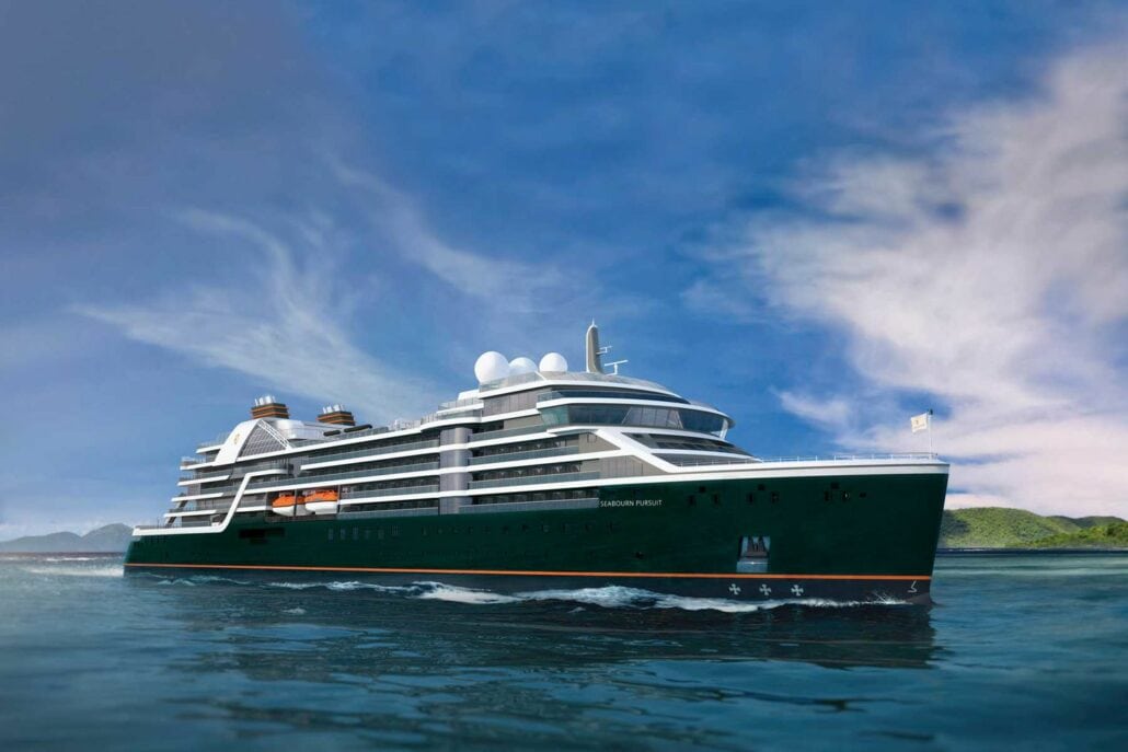 A large cruise expedition ship sails in calm waters under a clear blue sky. The century-old vessel is painted dark green with white upper decks. Small hills rise gently in the distant background.