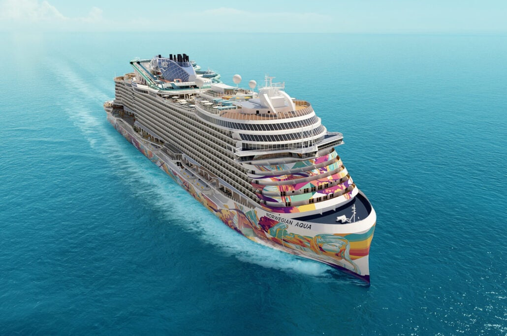 The Norwegian Aqua, with its colorful hull design, sails through a calm blue ocean under a clear sky. This cruise ship boasts multiple decks, pools, and a distinctive central funnel reminiscent of Modern Family's captivating blend of style and charm.