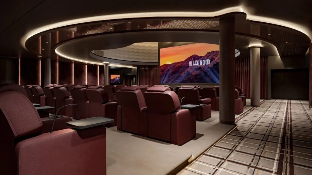 A modern entertainment venue features a cinema room with rows of plush, burgundy reclining seats. A large screen displays a view of a mountainous landscape with "HOLLYWOOD" in bold letters. Ceiling lights create a serene ambiance, perfect for enjoying an upgraded cinematic dining experience.
