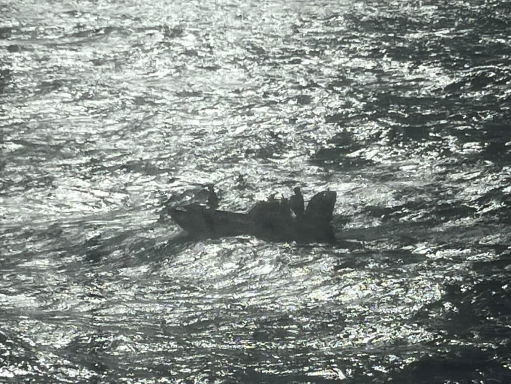 A small boat surrounded by choppy, sunlit waters, where silhouetted crew members are visible onboard. The waves glisten in the bright light, mirroring the excitement of a Royal Caribbean adventure.