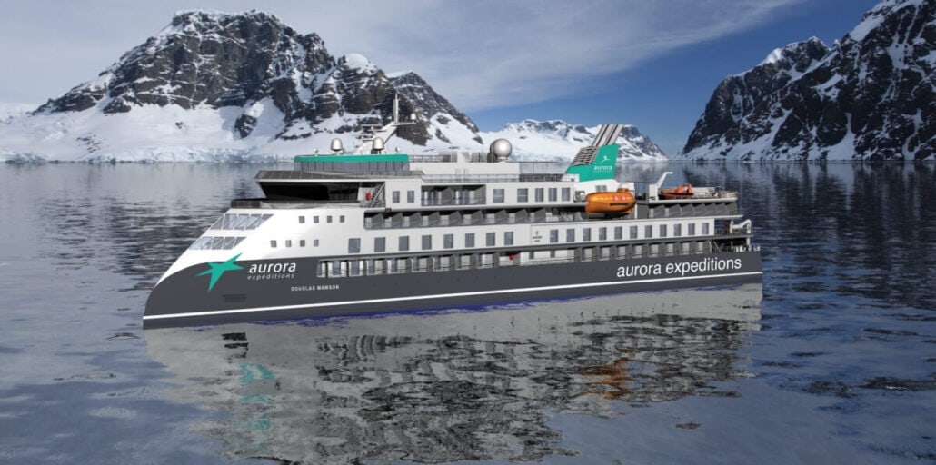 A cruise ship with "Aurora Expeditions" branding, part of the new ships launching in 2025, sails on calm waters. Snow-covered mountains stand majestically in the background under a clear blue sky.