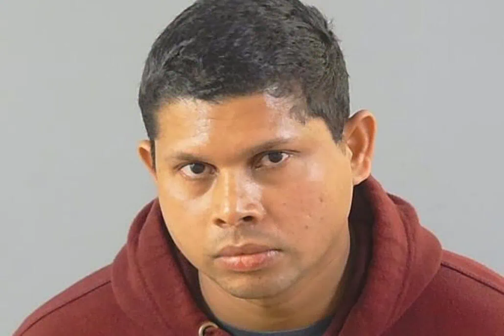 A person with short dark hair is wearing a maroon hoodie and looking directly at the camera against a gray background, reminiscent of a cruise ship chef taking a moment away from bustling kitchens aboard the Sky Princess.