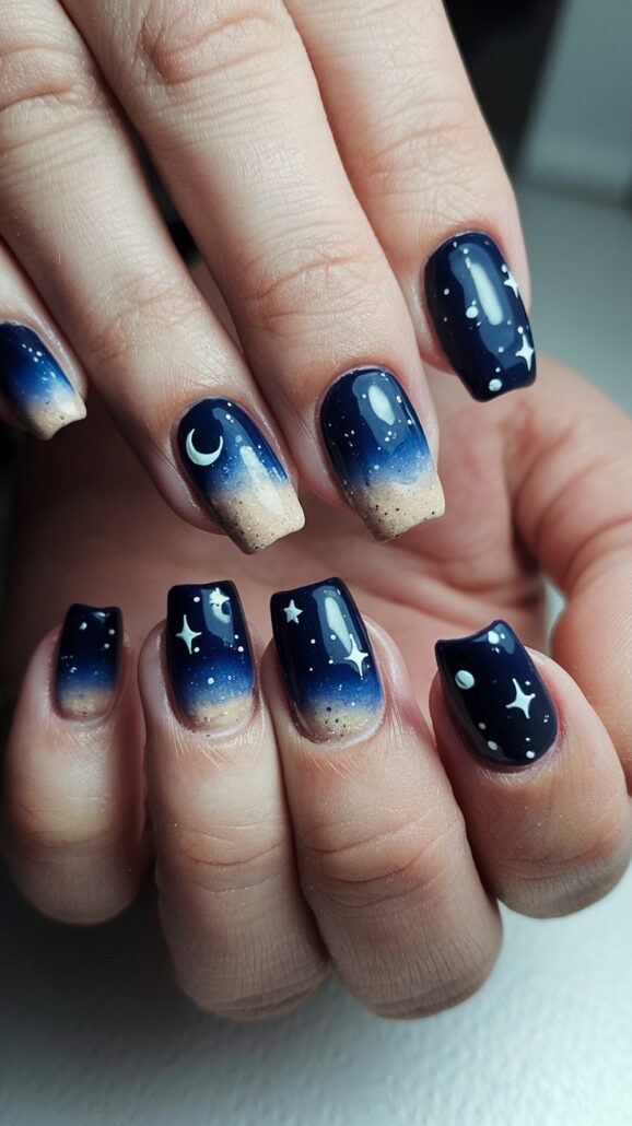 Close-up of hands with nails showcasing one of the best designs: a night sky theme. These cruise nails feature a gradient from dark blue to tan, adorned with white stars, crescent moons, and cloud-like shapes, perfect for those dreaming of The Bahamas. Medium length and meticulously manicured.