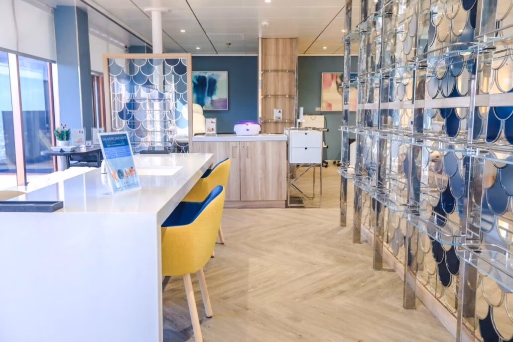 The modern dental office, reminiscent of a ship's enhanced service during dry dock, features large windows, wooden flooring, and glass partitions. A long desk with a white countertop and vibrant yellow chairs sits at the forefront, adding to the light and airy interior design.