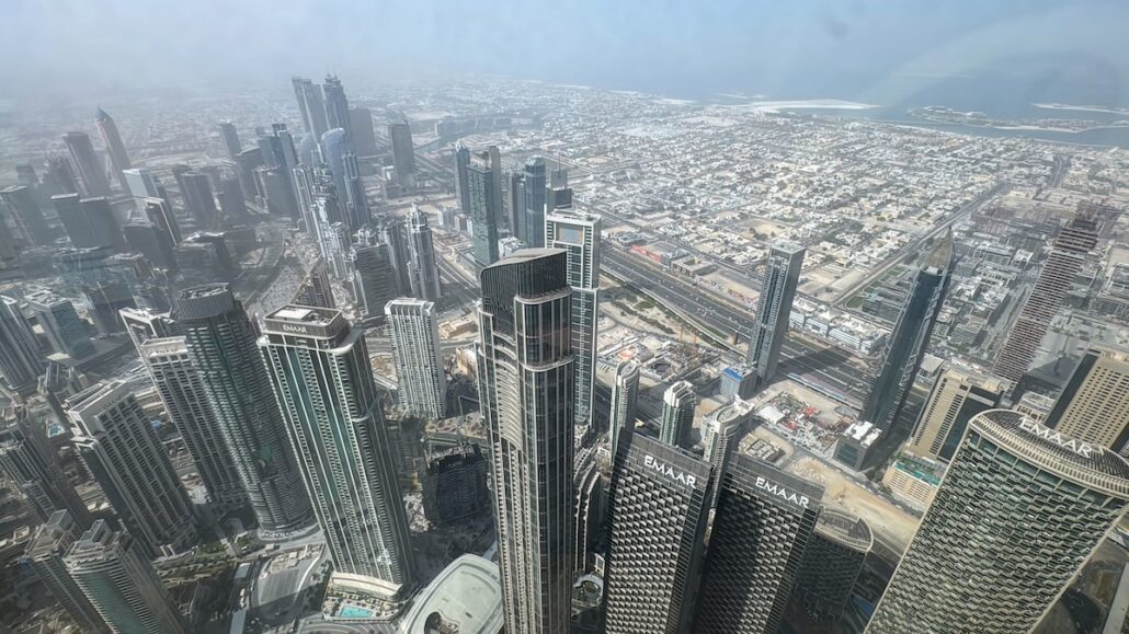 Captured from above, the urban landscape unfolds like a scene from a Celestyal Journey trip report, where numerous skyscrapers and high-rise buildings create a perfect balance in this midsize city. The skyline is dominated by tall structures, with the hazy atmosphere adding an aura of infinite possibility.