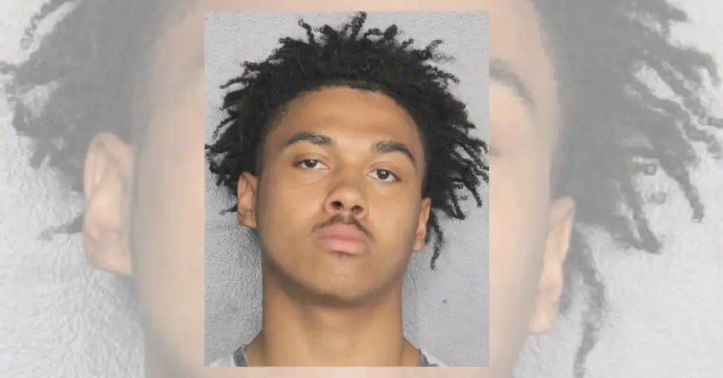 A young man with short, curly hair and a thin mustache is pictured in a headshot against a plain, light-colored background. The guest charged in the cruise ship elevator assault looks directly at the camera with a neutral expression.