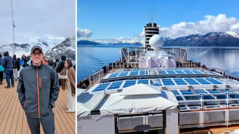 A cruise passenger in a gray jacket stands on the deck, surrounded by others, with mountains and water in the background beneath a partly cloudy sky. The scene captures the vibrant life of a $15,000 cruise.