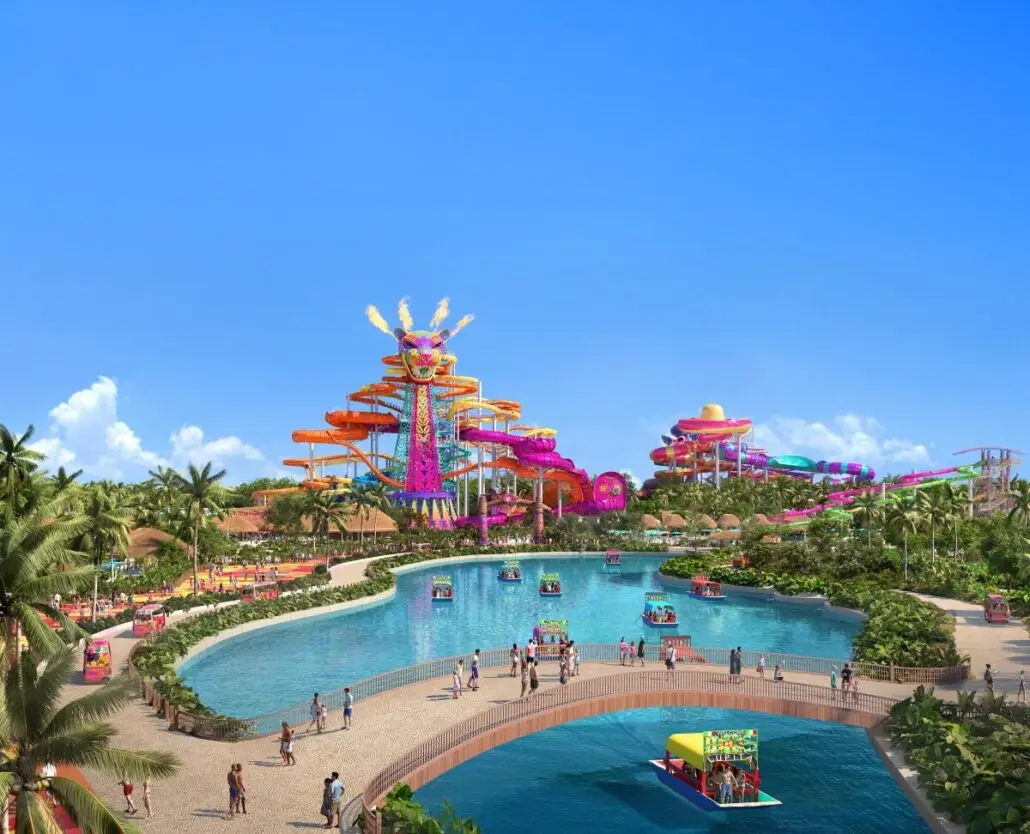 A large water park with colorful waterslides, a lazy river, and people walking on paths and bridges. The scene is bright with clear skies, tropical plants, and several floating cabanas on the water.