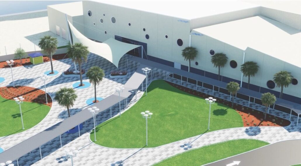 An outdoor area at Port Canaveral features green lawns, paved walkways, palm trees, and a modern building with circular windows and a white canopy—showcasing cruise terminal upgrades among landscaped sections and streetlights.